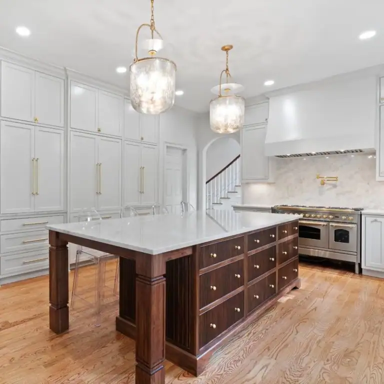 Kitchen Remodel - Walnut Island and White Cabinetry Sandy Springs, GA kitchen remodel with floor-to-ceiling white inset cabinetry, a walnut island topped in marble, glass pendant lights, a pro-style range with brass trim and red oak floors